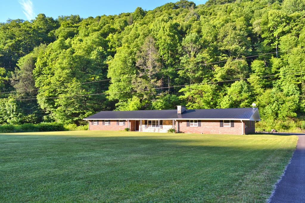 Enjoy the beauty of the country in this rambling ranch style home cradled in a spectacular 5+ acre creekfront setting in the Grayson Highlands. This home offers room to roam with one level living, handicapped accessible, and located just minutes from Grayson Highlands Park, horse trails, the New River, and other High Country destinations.  Currently set up with 5-bedrooms and 2-baths, this home has many possibilities. The floor plan includes a spacious living area with a unique stone wood burning fireplace as its focal point, a generously sized kitchen with informal dining area, a bonus room suitable for 5th bedroom, office, studio, or home gym, and 4 bedrooms, 2-baths, laundry & utility room.  All easily accessed with updates that include new flooring in most rooms, updated plumbing, metal roof, & more.  All of this and situated on a 5.299 acre setting on the banks of Big Wilson Creek with big level lawn, garden or pasture area for your horse, and woodlands full of wildlife.