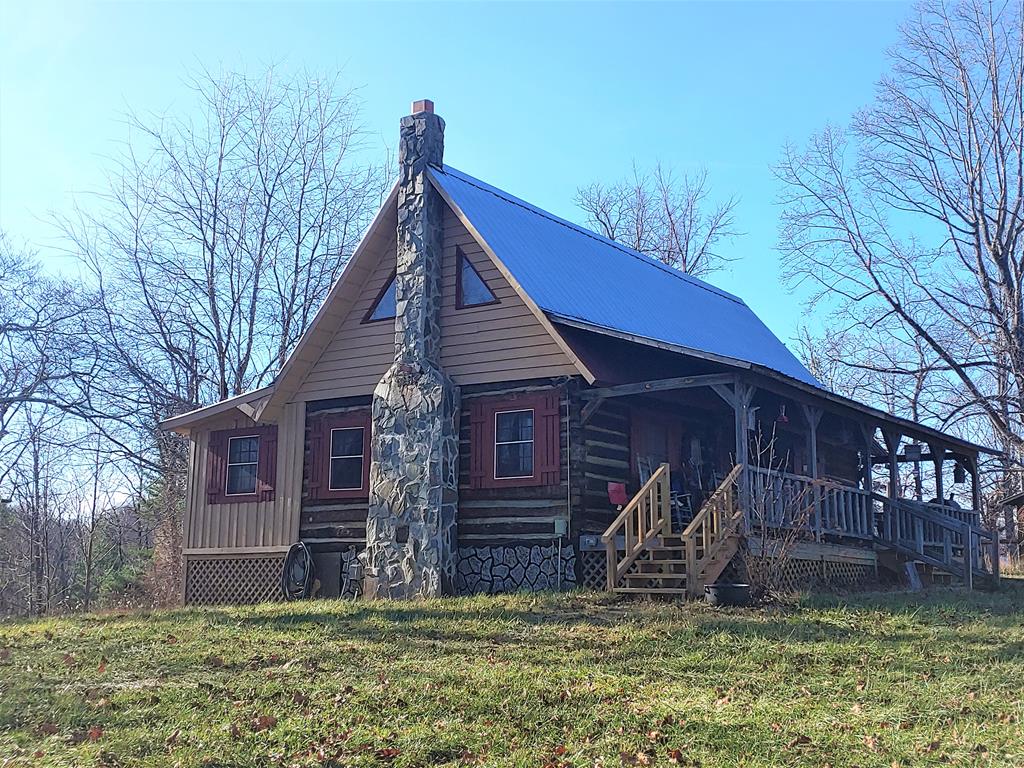 Nestled in the mountains of Elk Creek Virginia is this spectacular rustic cabin on 4.35 acres. Step back in time and sit on the covered front porch and enjoy the GORGEOUS VIEW of the Iron Mountain Ridgeline. Warm up in the winter with the new wood-burning stove or the propane floor ducted heat which heats the home as well. In the summer months there is also air an conditioning unit as central AC. Authentic rustic charm on display throughout this home with beautiful beamed vaulted ceilings which allow plenty of light as to not make this cabin dark inside. Large 1 bedroom and the log stairway leads you up to the huge loft area where you have room for 2-4 more twin beds as the current owner's have it set up now. 2 full bathrooms. One bath has a clawfoot tub with a shower attachment.  This open concept cabin flows into the large kitchen/dining combo area with plenty of space and cabinets for storage. New wood burning stove and all new ductwork. Multiple outbuildings on property.